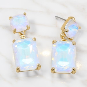 May include: A pair of drop earrings featuring gold-tone metal settings and iridescent, light-reflecting stones. Each earring consists of a smaller square-cut stone at the top and a larger rectangular-cut stone suspended below by a small gold link.