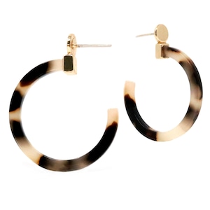 May include: A pair of gold hoop earrings with a tortoiseshell pattern. The earrings are made of a thick, durable material and have a simple, elegant design.