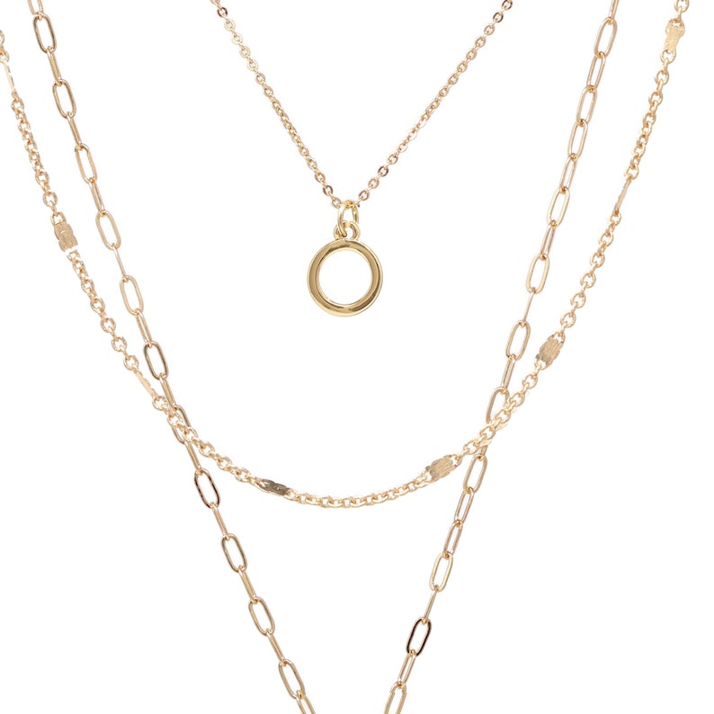 A gold layered necklace with a circle pendant. The necklace has three chains of different lengths and styles.