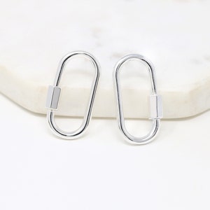 May include: A pair of silver oval-shaped clasps with a rectangular bar in the center.