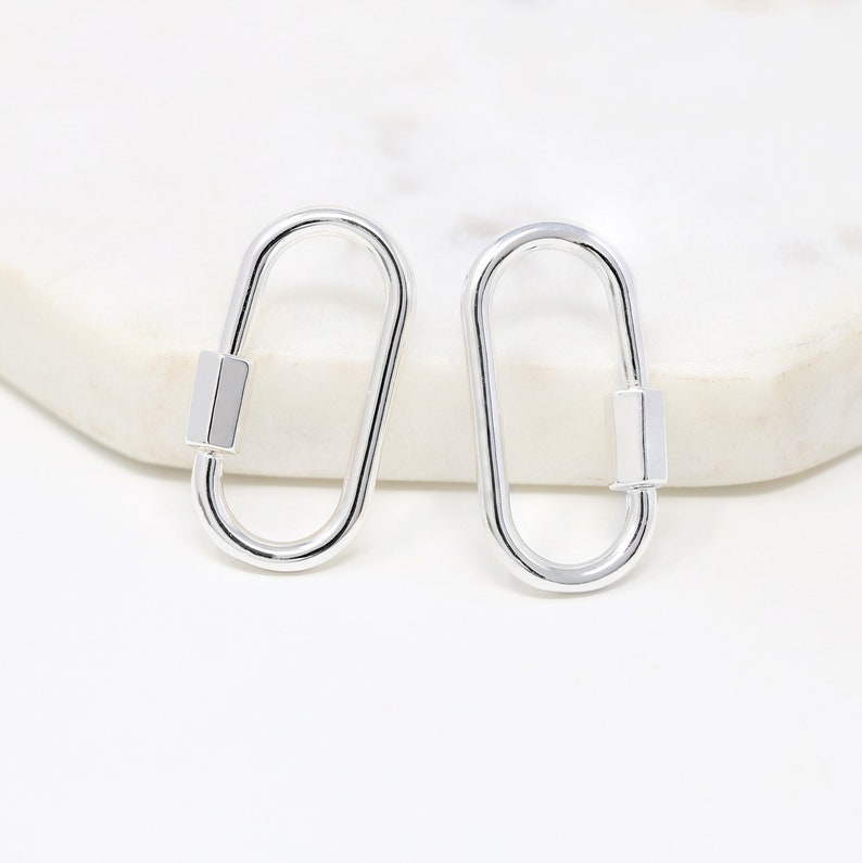 May include: A pair of silver oval-shaped clasps with a rectangular bar in the center.