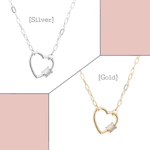 May include: Two silver and gold necklaces with heart-shaped pendants. The pendants have a small diamond-like stone in the center. The necklaces are labeled [Silver] and [Gold].