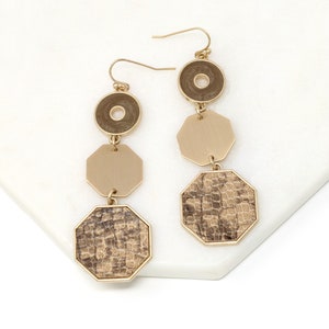 May include: Gold tone dangle earrings with three geometric shapes. The top shape is a circle with a smaller circle in the center. The middle shape is a hexagon. The bottom shape is a hexagon with a brown snakeskin pattern.
