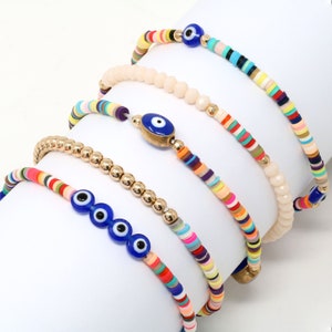 May include: Set of five colorful beaded bracelets with blue evil eye charms. The bracelets feature various patterns of colorful beads, including gold beads, and are perfect for stacking.