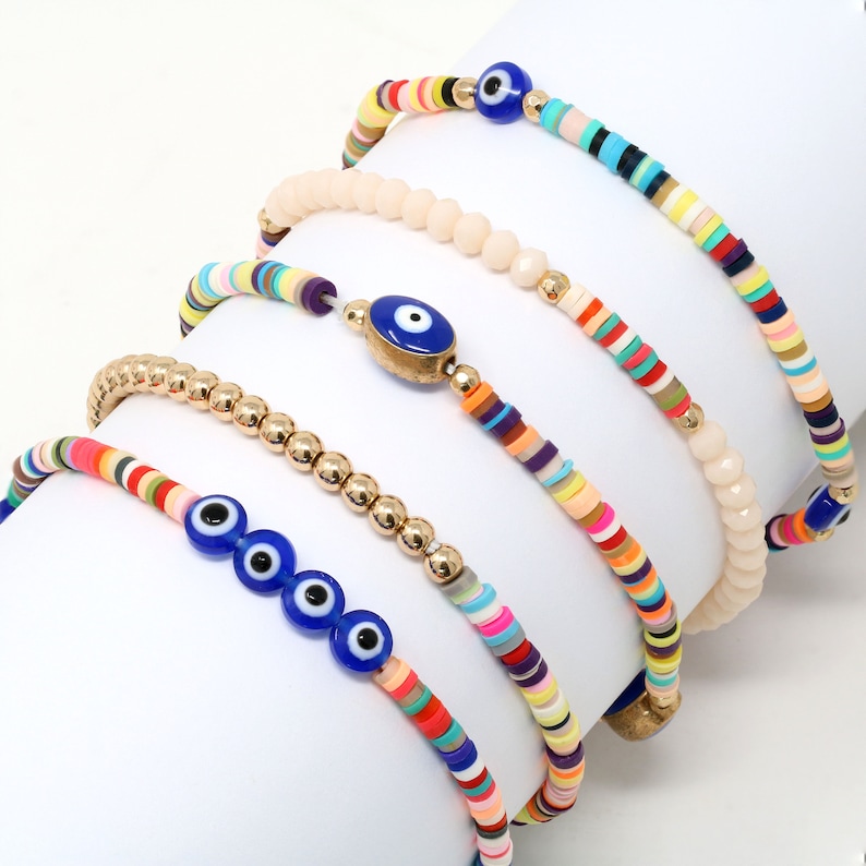 May include: Set of five colorful beaded bracelets with blue evil eye charms. The bracelets feature various patterns of colorful beads, including gold beads, and are perfect for stacking.