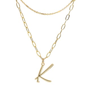Puede incluir: Un collar de cadena de oro con una cadena delicada y una cadena m&aacute;s grande. La cadena m&aacute;s grande tiene un colgante de oro con la letra K.