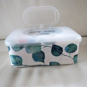 Könnte beinhalten: Eine weiße Plastik-Tischtuchbox mit einem durchsichtigen Deckel und einem grün-weißen Blumendesign. Der Deckel hat einen Griff zum einfachen Öffnen.