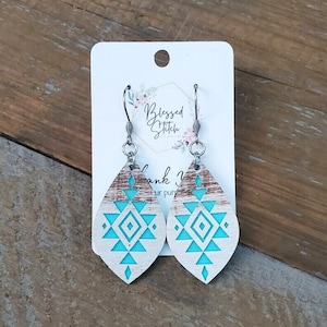 May include: Teal and white geometric pattern wooden dangle earrings with silver hooks. The earrings are on a white card with the text "Blessed Stitch Studio" and "Thank You for your purchase".