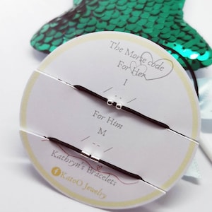 May include: Two black elastic bracelets with silver beads, displayed on a white circular card with the text "The Morse code For Her I ... For Him M ..." and "Kathryn's Bracelets KatoO Jewelry".