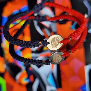 Può includere: Due braccialetti dell'amicizia con cordini rossi e blu navy. Ogni braccialetto ha un ciondolo d'argento con un design di Spiderman.