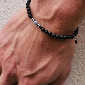 May include: A black lava rock bracelet with a silver bead and a gray stone bead.