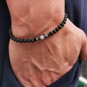 May include: A black lava rock bracelet with a silver bead and a light blue gemstone bead.