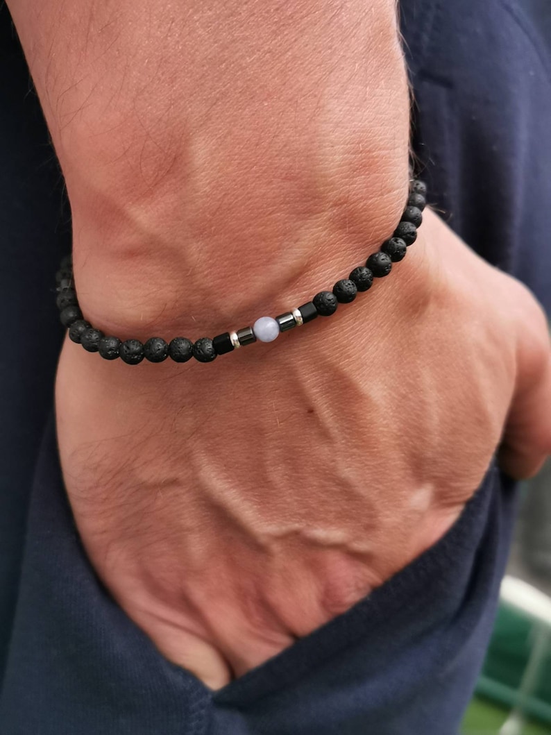 May include: A black lava rock bracelet with a silver bead and a light blue gemstone bead.