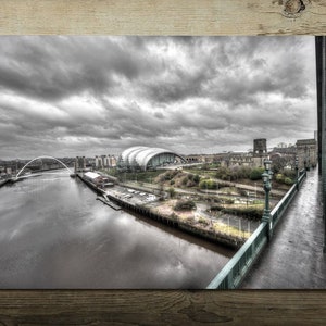 Puede incluir: Una fotografía en blanco y negro de un horizonte de ciudad con un río y un puente. La foto fue tomada desde un puente mirando hacia abajo al río y la ciudad.