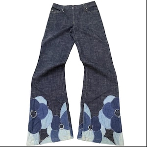 Op de afbeelding: Donkerblauwe denim jeans met een uitlopende pijp. De jeans hebben grote, geappliqueerde bloemmotieven in blauwtinten aan de zoom. De jeans hebben een klassiek ontwerp met vijf zakken en een knoop- en ritssluiting.