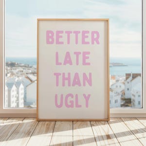 May include: A framed print with the text "Better Late Than Ugly" in pink letters on a white background.