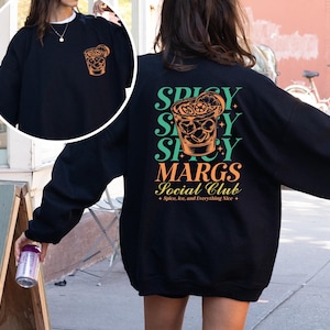 May include: Black sweatshirt with a graphic of a margarita glass and the text "Spicy, Spicy, Spicy Margs Social Club - Spice, Ice, and Everything Nice" printed on the back.