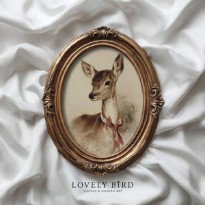 Puede incluir: Impresión artística vintage enmarcada ovalada con un ciervo con una cinta rosa. La obra de arte está sobre un fondo crema y enmarcada en un marco ovalado dorado y ornamentado. El texto "LOVELY BIRD" y "VINTAGE & MODERN ART" está en la parte inferior.