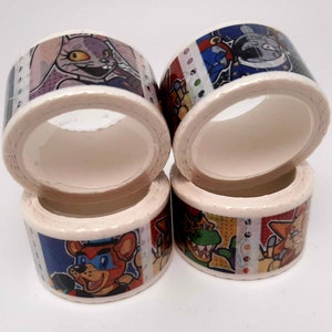 May include: Four rolls of colorful washi tape featuring cartoon characters. The tape is white with a variety of colorful designs, including a bunny, a bear, a dragon, and a fox.