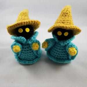 Puede incluir: Dos peluches de mago negro de crochet con sombreros amarillos y túnicas azules. Los peluches tienen ojos amarillos y están de pie sobre una superficie blanca.