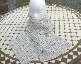 May include: A light gray knitted scarf with a textured pattern and small flecks of color. The scarf is draped around a white mannequin head, showcasing its design. The scarf's dimensions are approximately 70 inches long.