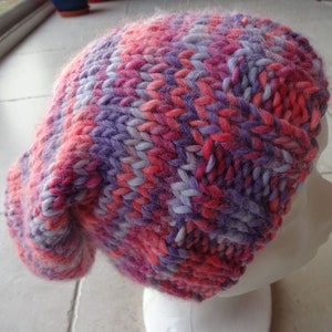 May include: A pink and purple knitted beanie hat with a slouchy fit.