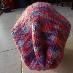 May include: A pink and purple striped knitted hat. The hat is made of soft yarn and has a slouchy fit.