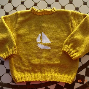 May include: A yellow knitted sweater with a white sailboat design on the front.