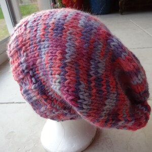 May include: A pink, purple and white striped knitted beanie hat.