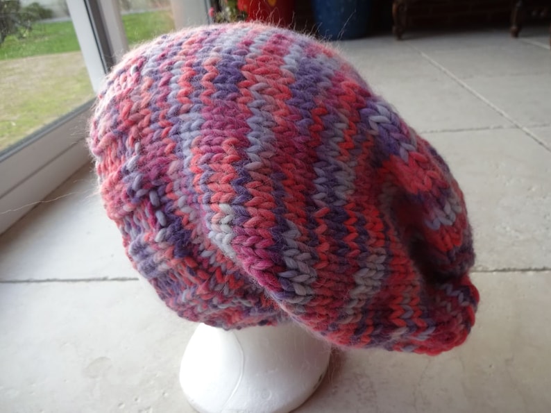 May include: A pink, purple and white striped knitted beanie hat.