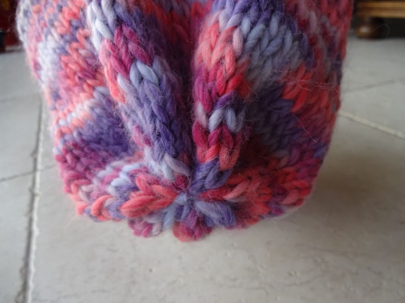May include: Close-up of a knitted hat with a pink, purple and white colour pattern.