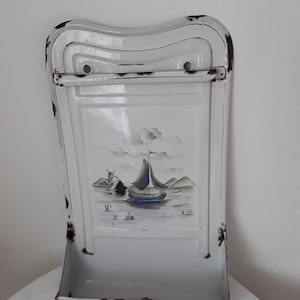 Può includere: Scaffale da cucina a parete in smalto bianco con una scena dipinta di una barca a vela e un mulino a vento su uno specchio d'acqua. Lo scaffale ha uno ripiano e un portasciugamani.
