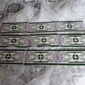 Peut inclure: Un ensemble de six carreaux de céramique vintage avec un motif répétitif de fleurs vertes, blanches et violettes. Les carreaux sont parfaits pour ajouter une touche de charme vintage à n'importe quel espace.