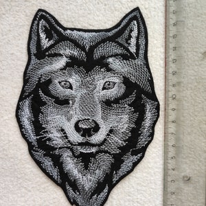 May include: A black and white embroidered wolf head patch. The patch is approximately 10 cm wide and 12 cm tall.