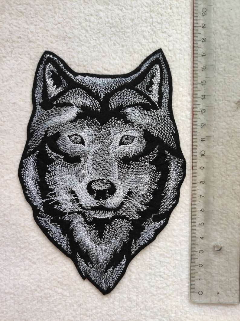 May include: A black and white embroidered wolf head patch. The patch is approximately 10 cm wide and 12 cm tall.