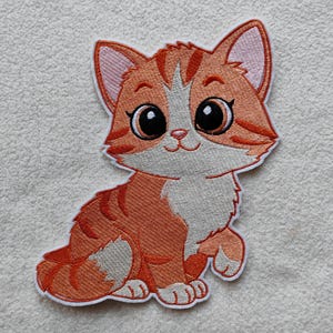 Könnte beinhalten: Gestickter Aufnäher mit einer Cartoon-Katze in Orange mit großen, ausdrucksstarken Augen. Die Katze hat weiße Markierungen und orangefarbene Streifen. Der Aufnäher ist weiß umrandet und hat einen freundlichen Ausdruck.