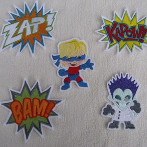 Könnte beinhalten: Fünf gestickte Bügelbilder mit einem Superhelden, einem Wissenschaftler und drei Comic-Soundeffekten: "BAM!" "KAPOW!" und "ZAP!"