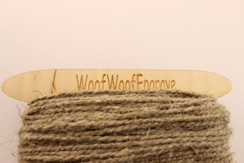 May include: A spool of natural brown twine with a wooden label that reads "Woof Woof Engrave".