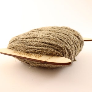 May include: A ball of natural brown twine wrapped around two wooden dowels with the text "Wool Winding" printed on the dowels.