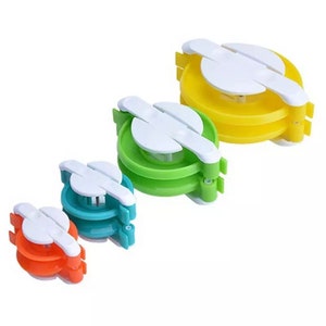 May include: Four yarn ball winders in different sizes. The winders are made of plastic and have a white centre with a yellow, green, blue, and orange outer ring.