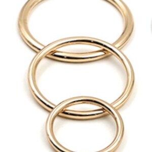 May include: Three gold-colored metal rings of different sizes, nested inside each other.