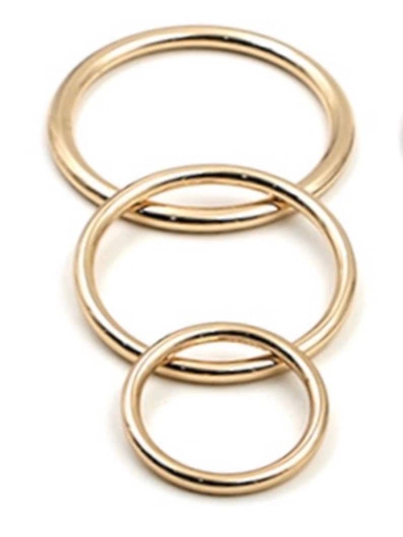 May include: Three gold-colored metal rings of different sizes, nested inside each other.