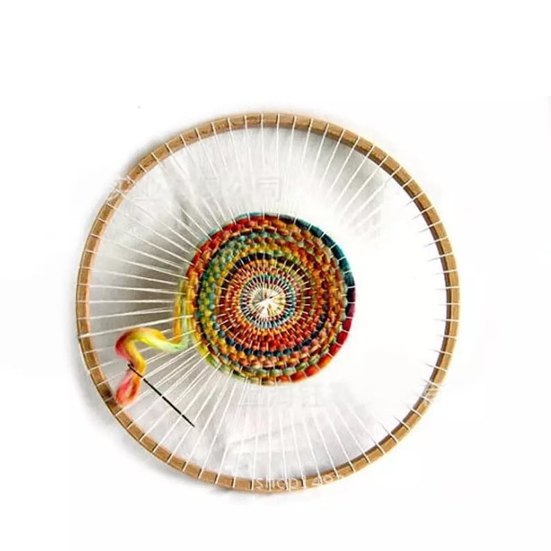 May include: A circular wooden loom with a colorful woven tapestry in the center. The tapestry is made with a variety of colored yarns and has a spiral pattern. A needle and yarn are visible in the loom.