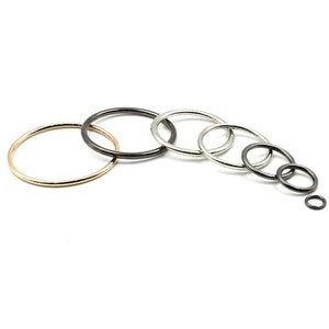 May include: A set of seven metal jump rings in various sizes. The rings are in gold, silver, and black.
