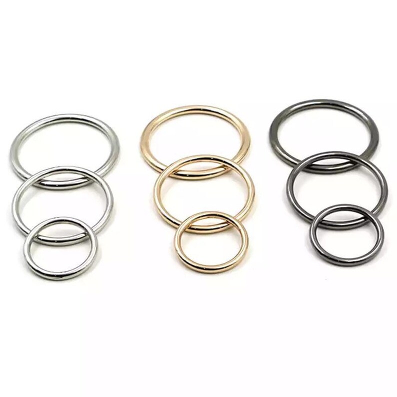 May include: Three sets of metal rings in silver, gold, and black. Each set has three rings of different sizes.