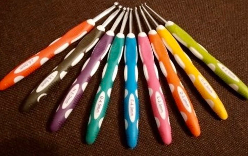 May include: A set of nine crochet hooks arranged in a fan pattern, each featuring a metallic hook and a colorful ergonomic handle with white oval accents. The handles are labeled with sizes ranging from 2.0mm to 6.0mm in various bright colors.