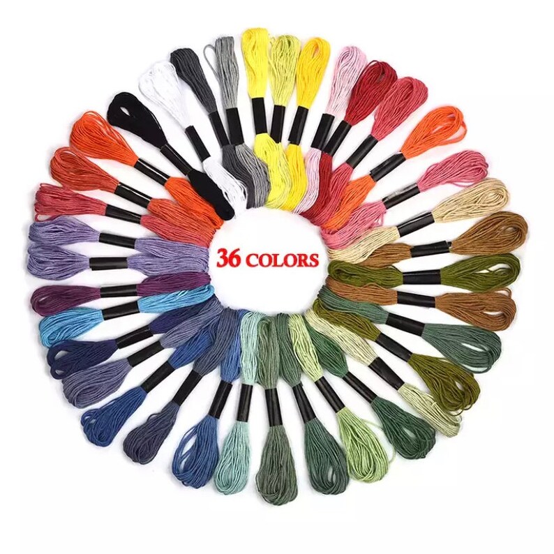 Puede incluir: Un conjunto de 36 carretes de hilo de bordar de varios colores, dispuestos en c&iacute;rculo. Los carretes est&aacute;n enrollados con hilos de diferentes colores, incluyendo rojo, naranja, amarillo, verde, azul, morado, marr&oacute;n y blanco.