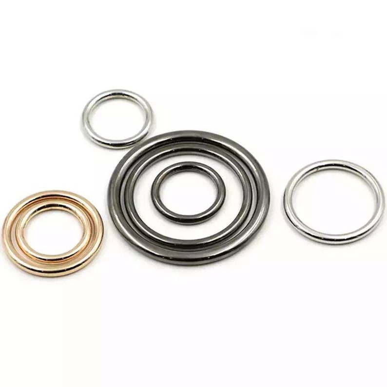 May include: Five metal rings in different sizes and colors. The rings are silver, gold, and black.
