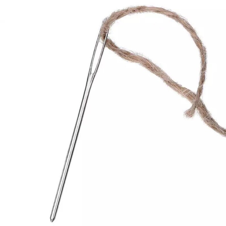 May include: A silver needle threaded with a brown twine string.