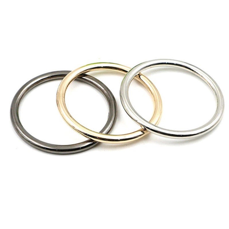 May include: Three metal rings in different finishes: black, gold, and silver. The rings are all the same size and are stacked on top of each other.